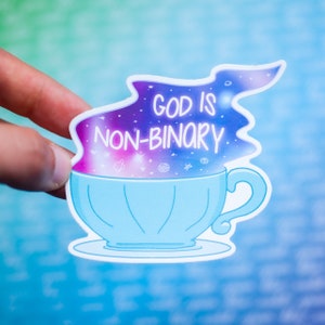 May include: A blue teacup with a galaxy design and the text "God is non-binary" inside the steam.