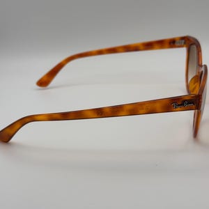 May include: Tortoiseshell sunglasses with brown gradient lenses. The Ray-Ban logo is visible on the temple. The frames are a warm brown colour with a classic, slightly oversized shape.