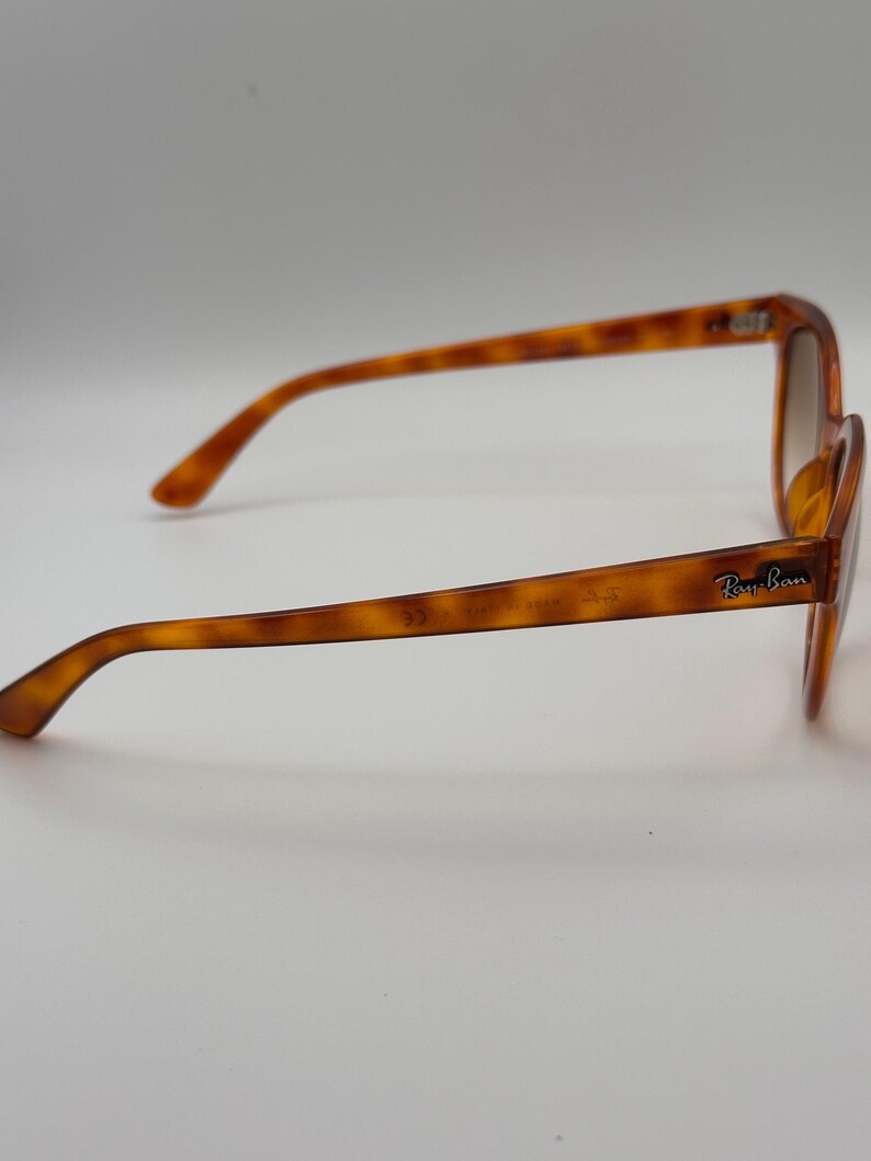 May include: Tortoiseshell sunglasses with brown gradient lenses. The Ray-Ban logo is visible on the temple. The frames are a warm brown colour with a classic, slightly oversized shape.