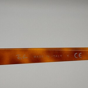 May include: Close-up of the arm of a pair of Ray-Ban sunglasses. The frame has a tortoiseshell pattern. The text "Ray-Ban" and "MADE IN ITALY" are visible on the arm.