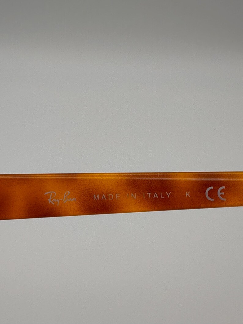 May include: Close-up of the arm of a pair of Ray-Ban sunglasses. The frame has a tortoiseshell pattern. The text "Ray-Ban" and "MADE IN ITALY" are visible on the arm.