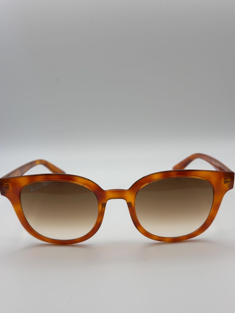May include: Brown tortoiseshell sunglasses with a rounded frame and gradient lenses. The sunglasses have a classic design and are suitable for everyday wear. The lenses transition from a darker shade at the top to a lighter shade at the bottom.