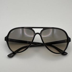 Puede incluir: Gafas de sol aviador negras con doble puente y lentes degradadas. Las gafas de sol tienen un dise&ntilde;o cl&aacute;sico con un aspecto elegante y moderno. El logotipo de Ray-Ban es visible en la lente superior izquierda.