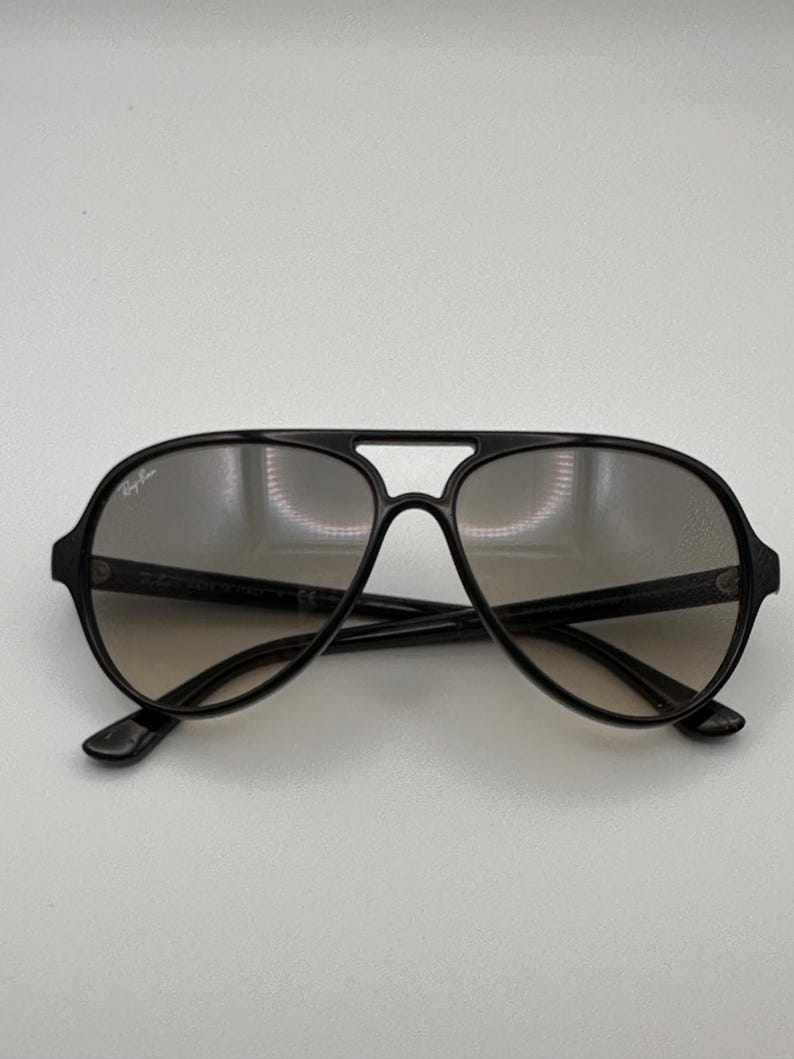 Puede incluir: Gafas de sol aviador negras con doble puente y lentes degradadas. Las gafas de sol tienen un dise&ntilde;o cl&aacute;sico con un aspecto elegante y moderno. El logotipo de Ray-Ban es visible en la lente superior izquierda.