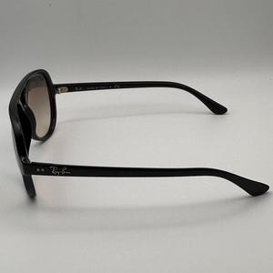 Puede incluir: Gafas de sol negras con montura cuadrada y lentes degradadas. El logotipo de Ray-Ban es visible en la patilla. Fabricado en Italia.