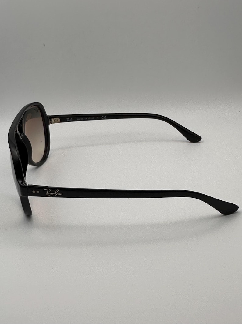 Puede incluir: Gafas de sol negras con montura cuadrada y lentes degradadas. El logotipo de Ray-Ban es visible en la patilla. Fabricado en Italia.