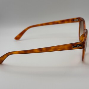 May include: Tortoiseshell sunglasses with brown lenses. The Ray-Ban logo is visible on the right arm. The frame has a classic, slightly rounded shape. The glasses are set against a plain white background.