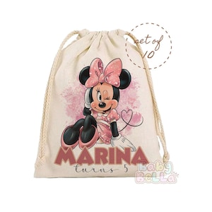 May include: A white drawstring bag with a pink Minnie Mouse design. The bag has the text "MARINA turns 5" and a pink heart. The bag is part of a set of 10.