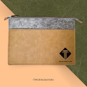 May include: A tan and gray zippered document case with a black pillar logo and the text "DAVIS FAMILY LAW." The bottom of the case has the text "-TWOENGRAVERS-". The case is made of leather and felt.