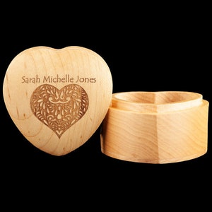 May include: A wooden heart-shaped box with a lid. The lid has a carved heart design and the name "Sarah Michelle Jones" engraved on it.