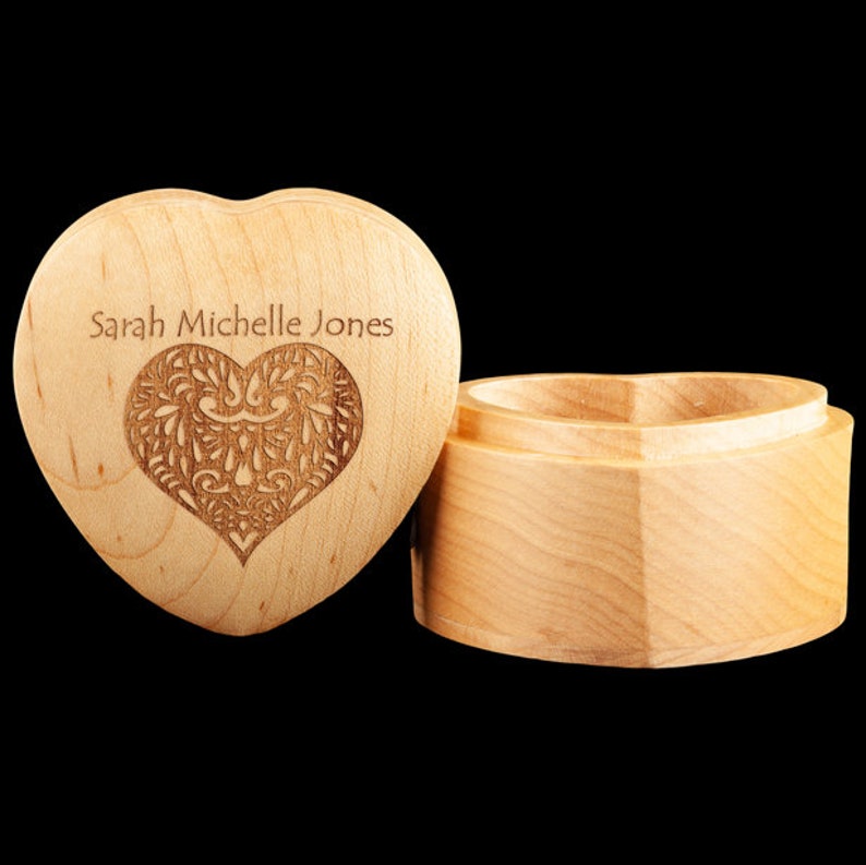 May include: A wooden heart-shaped box with a lid. The lid has a carved heart design and the name "Sarah Michelle Jones" engraved on it.