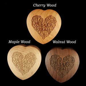 May include: Three heart-shaped wooden boxes with the words "I love you" engraved in a decorative script. The boxes are made of cherry, maple, and walnut wood.