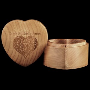 May include: A wooden heart-shaped box with an intricate carved design on the lid. The box is open and the inside is visible. The lid is engraved with the name "Sarah Michelle Jones".