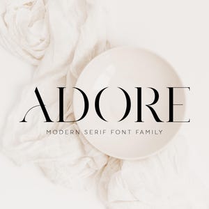 May include: A digital graphic featuring the word ADORE in a large black serif font, with the text MODERN SERIF FONT FAMILY in a smaller sans-serif font below it, layered over a cream-colored bowl and a draped white fabric background.