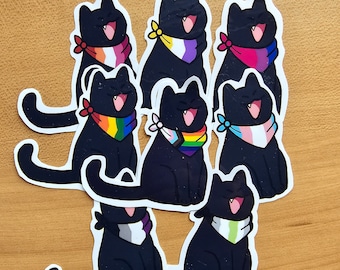 Op de afbeelding: Set van acht zwarte katten stickers met verschillende regenboogvlag ontwerpen. Elke kat draagt een bandana in een andere kleur met een regenboogvlag ontwerp. De bandana's zijn in de kleuren van de regenboog, transgender, lesbische, biseksuele, panseksuele, non-binaire en aseksuele regenboogvlaggen.
