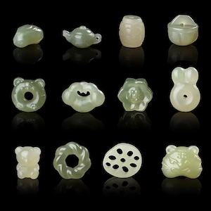 May include: A selection of pale green jade carvings, featuring designs such as a teapot, bear, and flower. The carvings are displayed on a black surface, showcasing their intricate details.