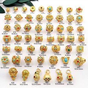 Peut inclure: Une collection de perles dorées de formes variées, rondes, carrées et cylindriques. De nombreuses perles présentent des accents turquoise et rouges. Les tailles varient de 5x5mm à 16x11mm.