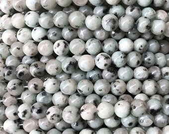 Puede incluir: Una hebra de cuentas redondas, moteadas de blanco y negro. Las cuentas están hechas de piedra natural y tienen un acabado liso y pulido.