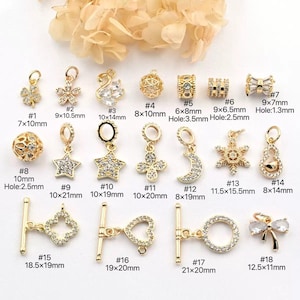 May include: A collection of gold-colored jewelry charms, including flowers, stars, a swan, and a bow. Some charms are encrusted with clear crystals. Sizes vary, with the largest being 0.83 x 0.79 inches. Ideal for jewelry making.
