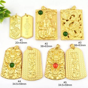 Puede incluir: Una colección de colgantes dorados con diseños intrincados, incluyendo dragones y figuras. Algunos colgantes presentan piedras preciosas incrustadas. Los tamaños varían de 20x43mm a 38x63mm, y 34.5x59mm. Se muestran sobre un fondo blanco.