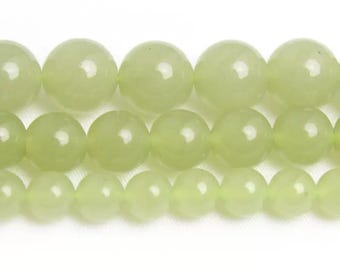 May include: Close-up of several rows of light green, spherical beads. The beads are of different sizes and have a smooth, shiny finish. The colour is a pale, soft green. The beads are strung together, likely for jewellery making.