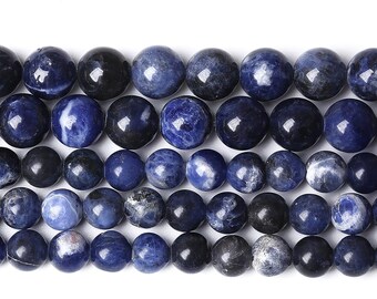 May include: Close-up of a strand of round, polished sodalite beads. The beads vary in shades of blue and black, with some displaying white marbling. These beads are suitable for jewelry making.
