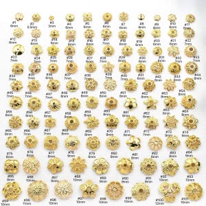 May include: A selection of 101 gold-coloured metal bead caps in diverse floral and geometric designs. Sizes range from 3mm to 12mm. Each cap is numbered for easy selection.