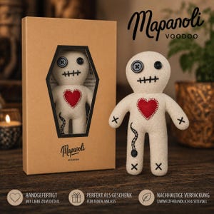 Può includere: Bambola voodoo beige con un cuore rosso, dettagli cuciti neri e occhi a bottone. La bambola è esposta accanto alla sua scatola a forma di bara, con il testo "Mapanoli Voodoo".