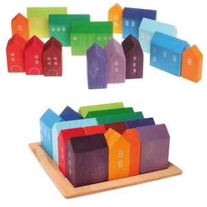 Puede incluir: Un conjunto de casas de juguete de madera de colores en varios tamaños y formas. Las casas están dispuestas en un patrón de arcoíris y están hechas de madera natural. Las casas son perfectas para el juego imaginativo y se pueden usar para crear un pueblo en miniatura.
