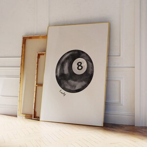 May include: A black and white watercolour illustration of a pool ball with the number 8 on it. The text "Lucky" is written below the ball.