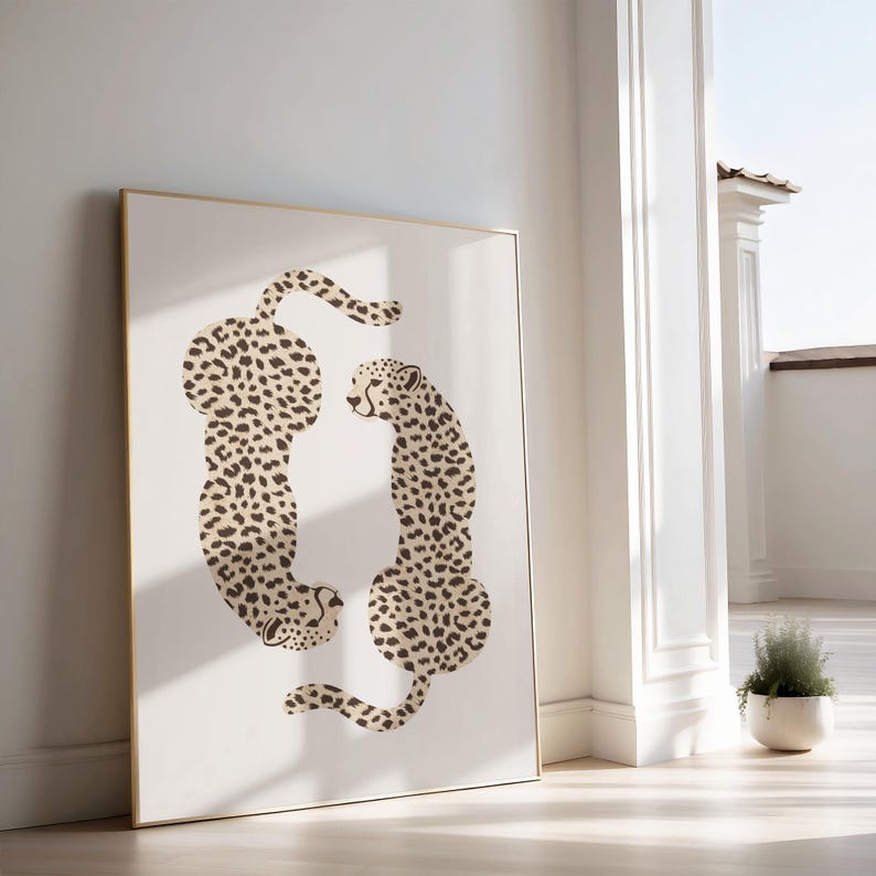 May include: A framed print of two cheetahs in a beige and brown spotted pattern, facing each other. The cheetahs are outlined in black and set against a white background.