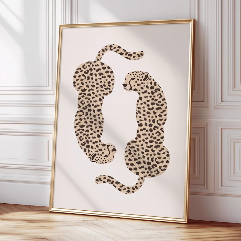May include: A minimalist art print featuring two stylized cheetahs in a circular formation on a light beige background. The cheetahs are depicted in black and brown spots against a white background.