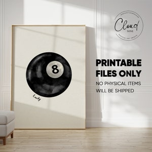 May include: A black and white watercolour illustration of a pool ball with the number 8 on it. The ball is surrounded by a black watercolour wash and the word "Lucky" is written below it.