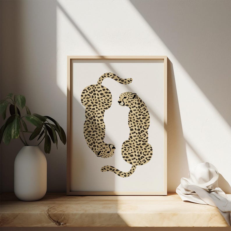 May include: A framed print of two cheetahs in a stylized design. The cheetahs are facing each other, with their tails intertwined. The background is white.