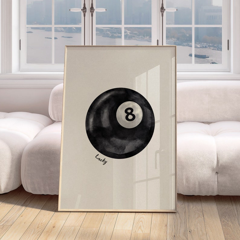 May include: A black and white watercolour illustration of a billiard ball with the number 8 on it. The ball is on a beige background with the word "Lucky" written below it.