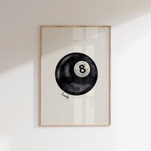 May include: A black and white watercolour illustration of a pool ball with the number 8 on it. The text "Lucky" is written below the ball.