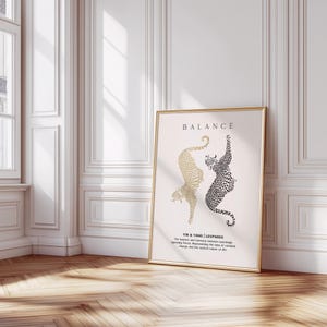 Peut inclure: Une impression encadr&eacute;e dor&eacute;e avec un fond blanc repr&eacute;sentant deux silhouettes de l&eacute;opards noires et dor&eacute;es se faisant face. Le texte "BALANCE" est en haut de l'impression et le texte "YIN & YANG | LEOPARDS" est en bas. Le texte sous les l&eacute;opards dit "L'&eacute;quilibre et l'harmonie entre des forces apparemment oppos&eacute;es, repr&eacute;sentant l'id&eacute;e du changement constant et de la nature cyclique de la vie."