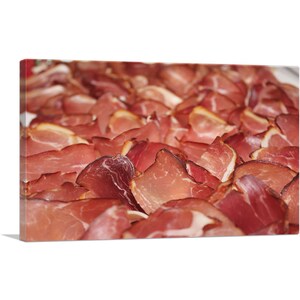 May include: Close-up of a platter of thinly sliced, cured meat. The meat is a deep red color and has a slightly marbled appearance. The slices are arranged in a neat, overlapping pattern.