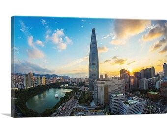 May include: A panoramic view of a city skyline with a tall, slender skyscraper in the center. The skyscraper is surrounded by other buildings and a body of water. The sun is setting in the background, casting a golden glow over the city.