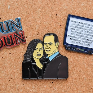 Könnte beinhalten: Drei Emaille-Pins mit Figuren aus der Fernsehserie Law & Order: Special Victims Unit. Der erste Pin ist ein blauer und roter Emaille-Pin mit dem Text "DUN DUN". Der zweite Pin ist ein schwarz-weißer Emaille-Pin mit einem Mann und einer Frau, die nebeneinander stehen. Der dritte Pin ist ein blauer Emaille-Pin mit einem Fernsehbildschirm mit Text über die Serie.