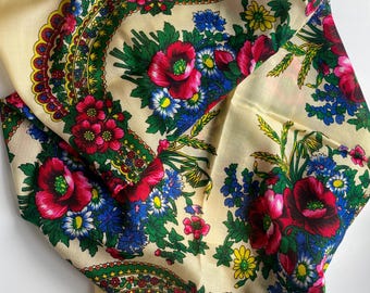 Peut inclure: Un foulard carré sur fond crème orné d'un motif floral éclatant. Le design présente de grands coquelicots rouges, des bleuets bleus et des marguerites jaunes entourés de feuillage vert et de bordures décoratives complexes en rouge et vert.