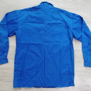 Pode incluir: Uma camisa azul s&oacute;lida de manga comprida com colarinho de bot&otilde;es.