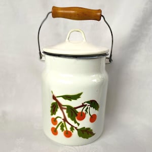 May include: A white enamelware milk can with a lid and a wire handle. The can features a cherry branch design in red, green, and brown. The handle is made of wood.