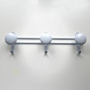 Op de afbeelding: Een witte metalen wandkapstok met drie haken. De kapstok heeft drie ronde, lichtgrijze knoppen en twee horizontale staven. De haken zijn onder de knoppen geplaatst en bieden een eenvoudig ontwerp om items op te hangen.