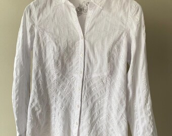 Peut inclure: Une chemise blanche à manches longues boutonnée, présentant une texture rayée verticale subtile sur la partie supérieure et un motif rayé diagonal sur la partie inférieure. Le vêtement comprend un col classique, une patte de boutonnage et des poignets.