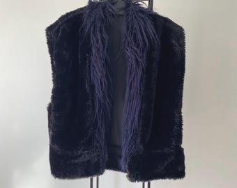 May include: A black faux fur vest with a shawl collar. The vest has a soft, plush texture and a relaxed fit.