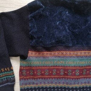 May include: A dark blue sweater with a colorful geometric pattern and a dark blue velvet patch on the back.