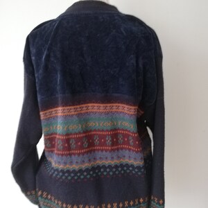 May include: A dark blue sweater with a colorful patterned design. The sweater has a velvet texture on the top half and a knit texture on the bottom half.