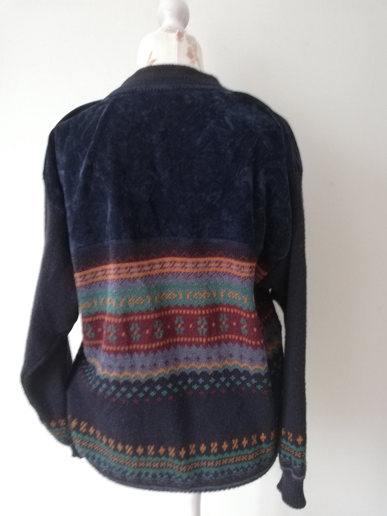 May include: A dark blue sweater with a colorful patterned design. The sweater has a velvet texture on the top half and a knit texture on the bottom half.