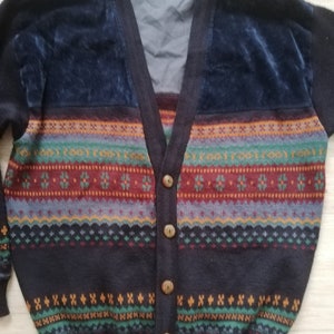 May include: A dark blue cardigan with a colorful striped pattern and brown buttons. The cardigan has a velvet panel on the front.